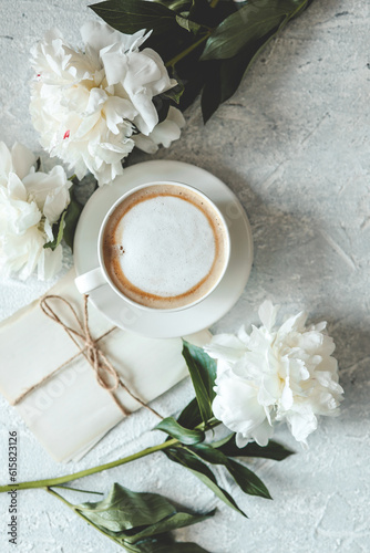 Summer composition top view. Cup of coffee, peonies and vintage letters on gray background