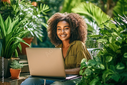 Ethnic woman sitting in a sunny garden, working on her laptop with a smile, ethnic woman working, business, natural light, affinity, bright background Generative AI