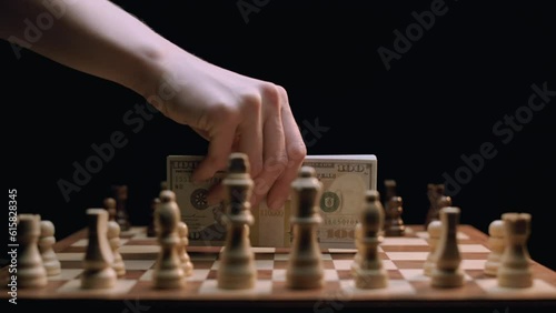 Caucasian Woman's Hand Places Stack of Money on Rotating Chess Board. Shot with ARRI Alexa in ArriRaw at 120 fps, exported 23.98 fps QuickTime Apple ProRes 422 HQ. photo