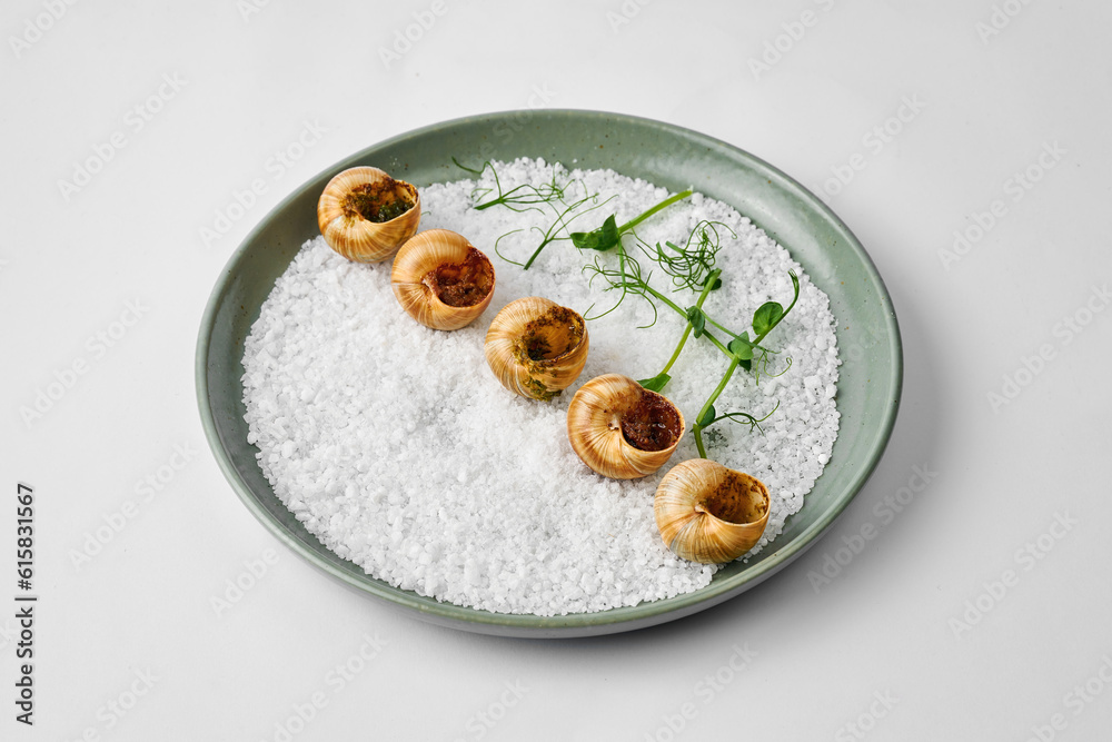 Baked snails Dijon style served on the table in a plate Baked snails Dijon style served on the table in a plate
