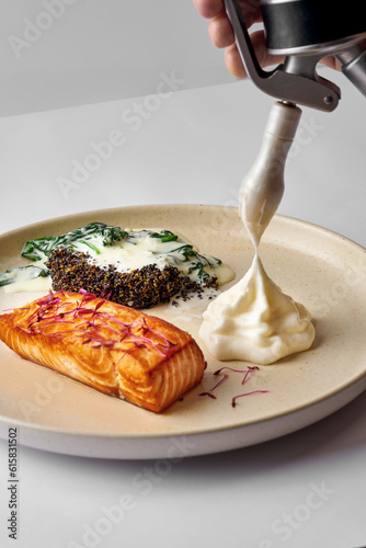 Salmon fillet with parmesan espuma, spinach and quinoa in a plate