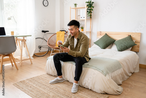 Young man sitting in bed shopping online with credit card.