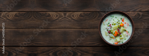 cheese soup in a clay plate on a wooden background. soup with young vegetables on a brown table. home cooking concept