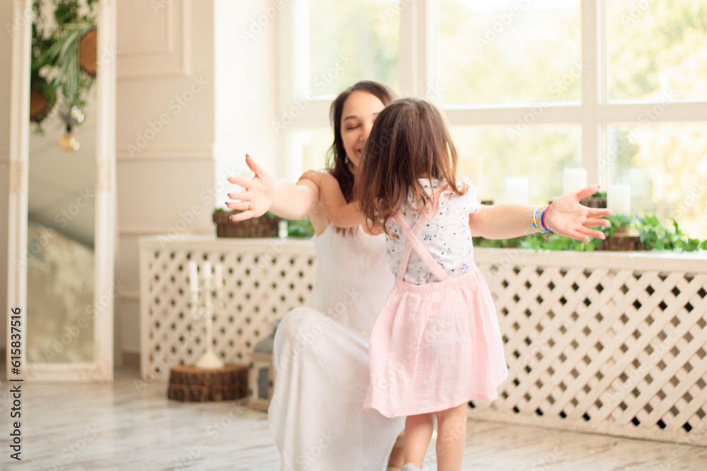 Child running into mother's hands to hug her. Family having fun in the park. Girl is happy to meet her mom. Background image. Child running into mother's hands to hug her. Family having fun in the park. Girl is happy to meet her mom. Background image.