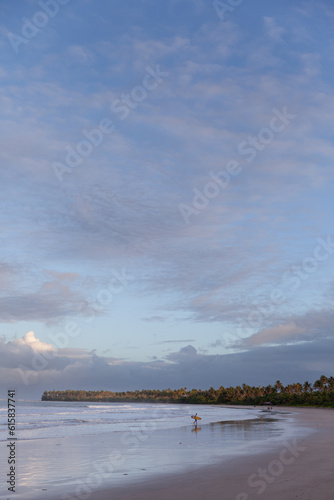 Silhouette of a surfer getting out of the water in Moreré, Bahia, Brazil
