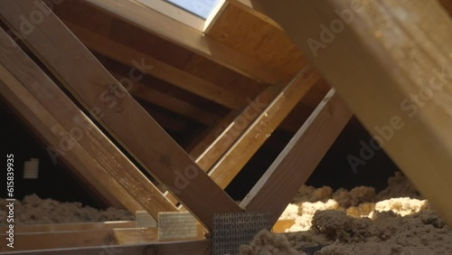 This panning video shows exposed beam and insulation in a house's attic. photo