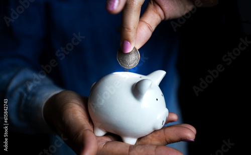 Wallpaper Mural woman putting coins in white piggy bank Saving money, financial concept. Saving Torontodigital.ca