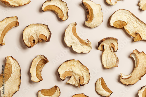 Dry slices of porcini as creative pattern, dehydrated food boletus mushrooms, top view, flat lay, beige background, minimal style. Natural food ingredient wild forest white mushroom, healthy eating