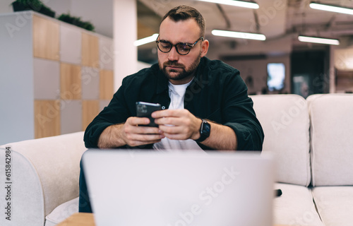 Focused man using smartphone in modern office