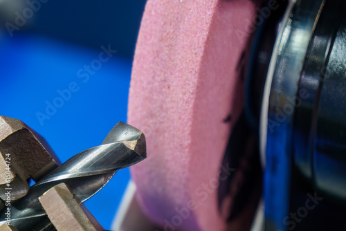 Close up scene the drill tool regrinding process with abrasive stone wheel. photo