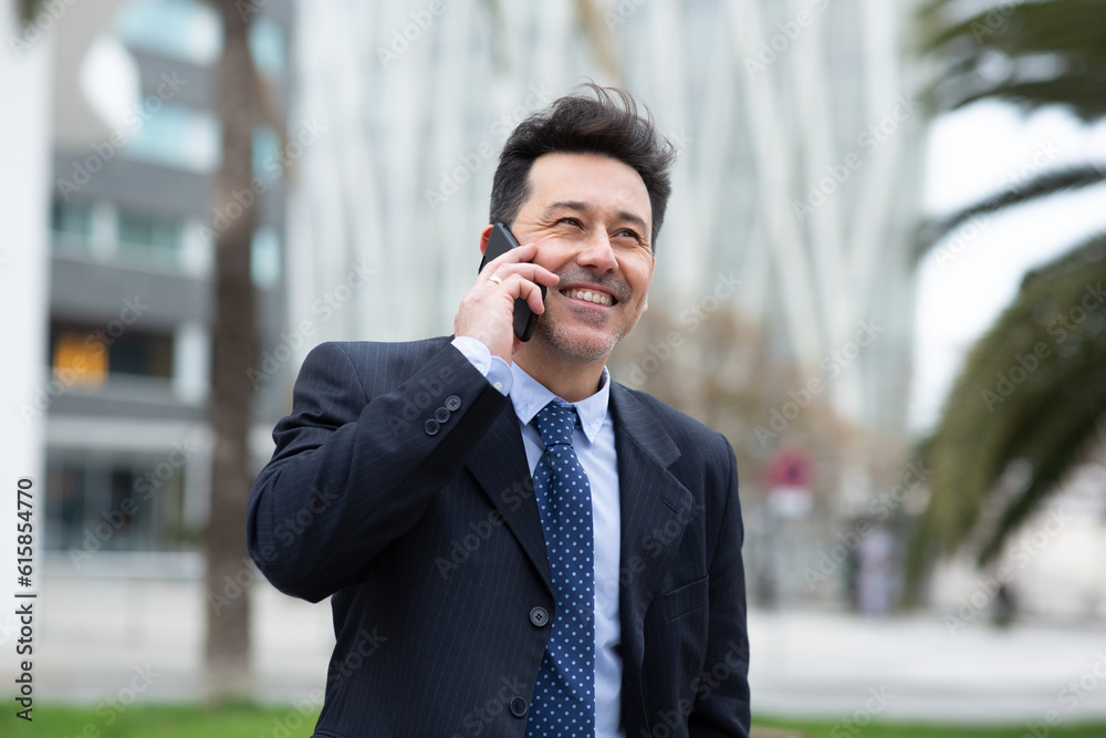Happy mature businessman talking on cellphone in the city Happy mature businessman talking on cellphone in the city