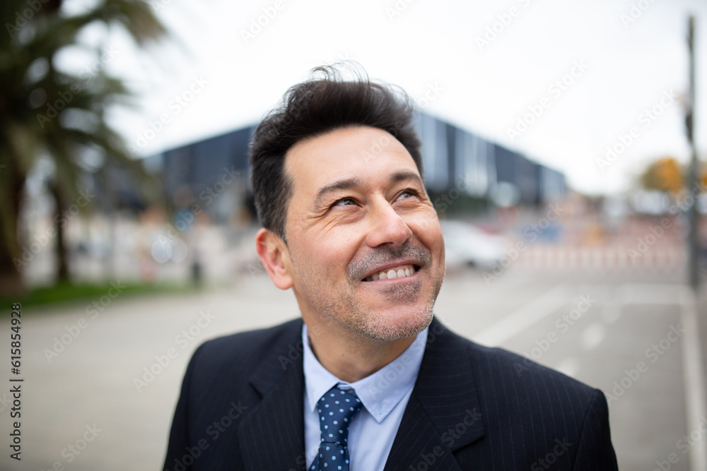 Handsome mature businessman looking away standing outside