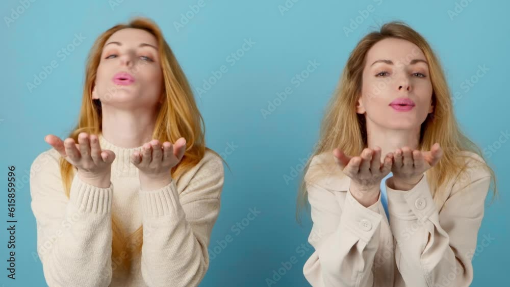Wink, flirt, friends and woman blowing a kiss, happy excited smiling. Two women sister lady friendly sending air kiss with confidence flirty emotion for cosmetics makeup in studio on blue background Wink, flirt, friends and woman blowing a kiss, happy excited smiling. Two women sister lady friendly sending air kiss with confidence flirty emotion for cosmetics makeup in studio on blue background