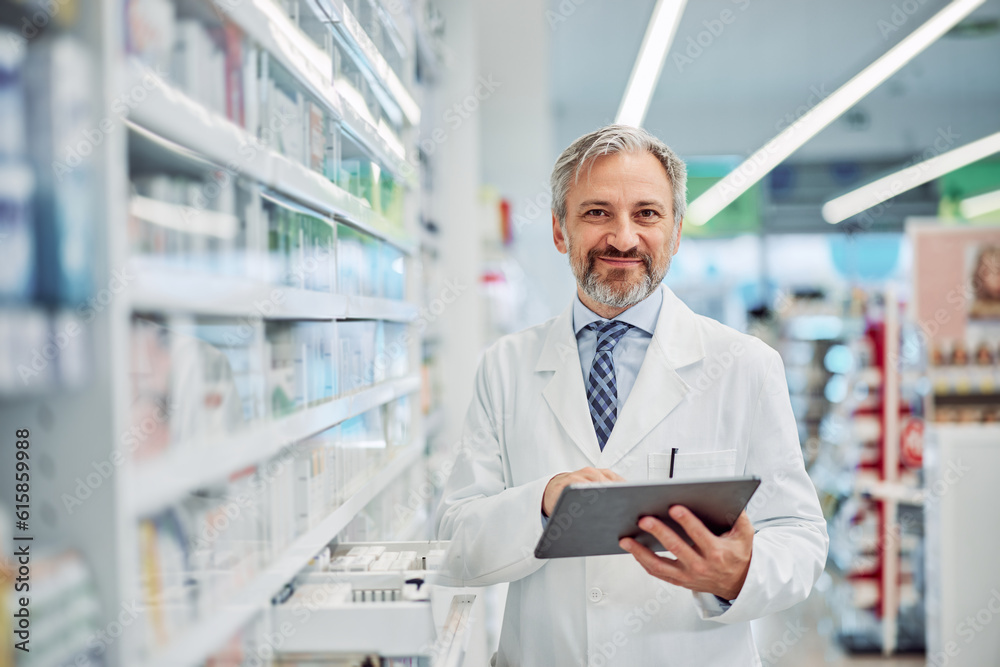 Portrait of a smiling senior male pharmacist holding a digital tablet.