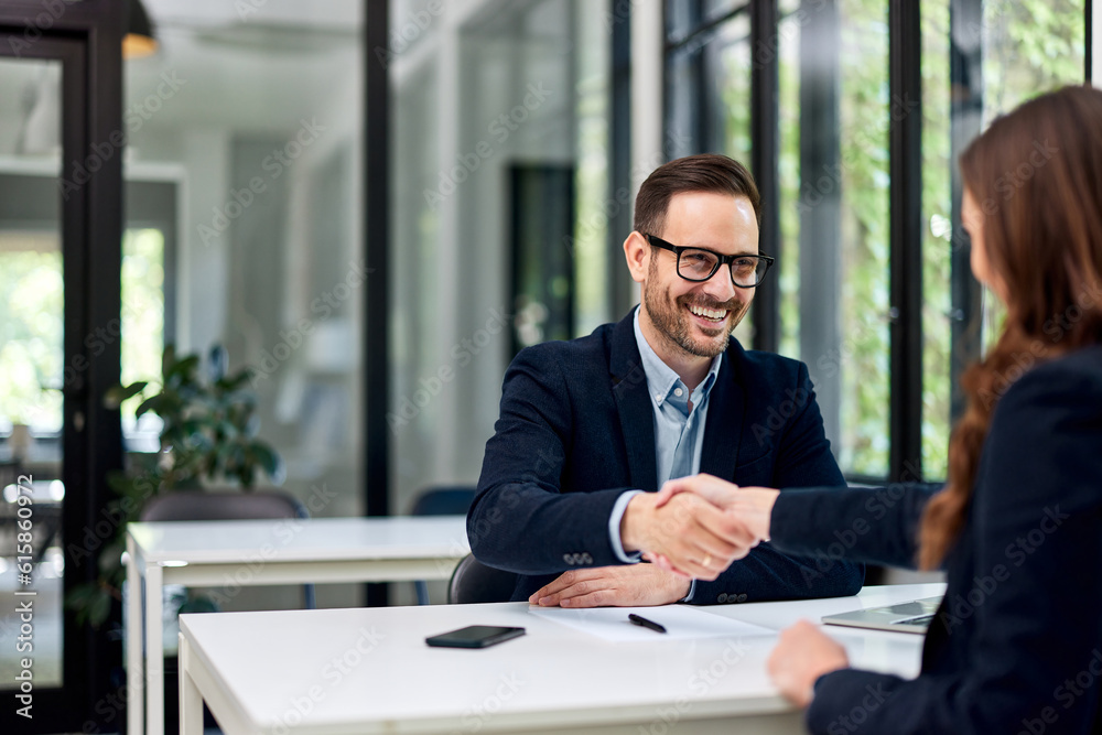 A businessman with glasses on a handshake with a woman after a business meeting. A businessman with glasses on a handshake with a woman after a business meeting.
