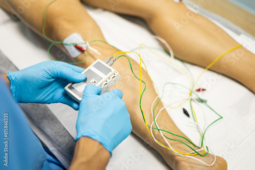 An unrecognizable physiotherapist is using the technique of electroacupuncture on a patient. Electrical stimulation in physiotherapy on the knee in a medical center.