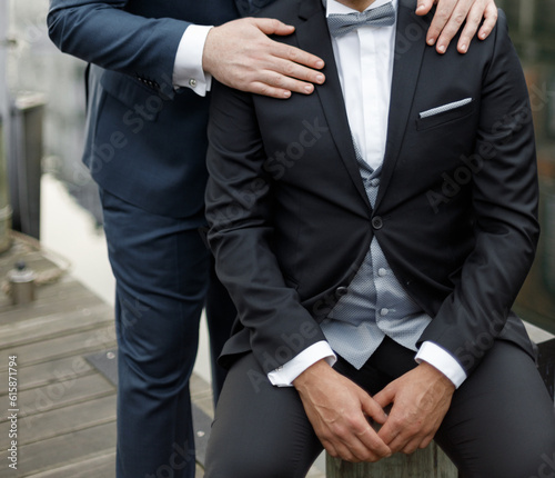 Gay couple wearing black and blue suits having a wedding, same sex couple marriage.