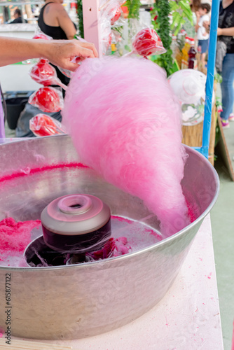 Woman making pink cotton candy at a street fair food stall.