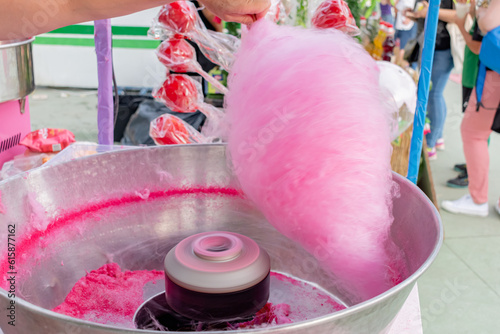 Woman making pink cotton candy at a street fair food stall.