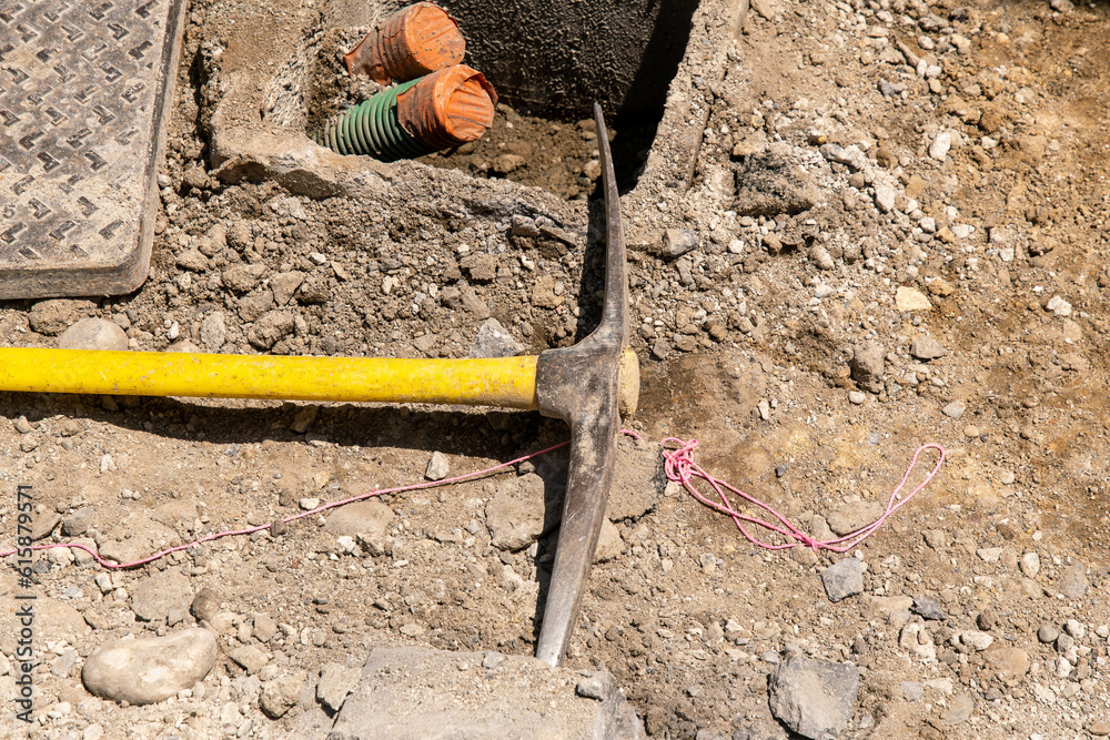 Pickaxe with yellow handle on the road at a construction site in the city Pickaxe with yellow handle on the road at a construction site in the city