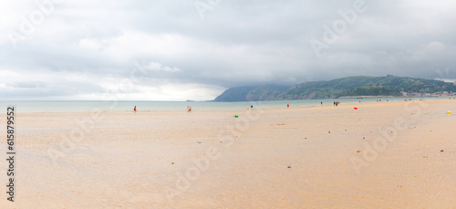 People walking on a wide beach on a cloudy morning  Laredo  Cantabria  Spain 
