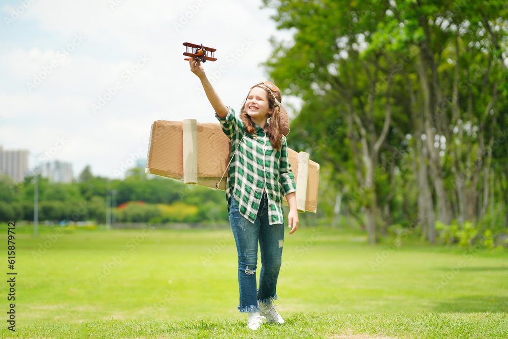 Obraz premium Portrait of red hair kid in pilot costume holding wooden plane running in summer field