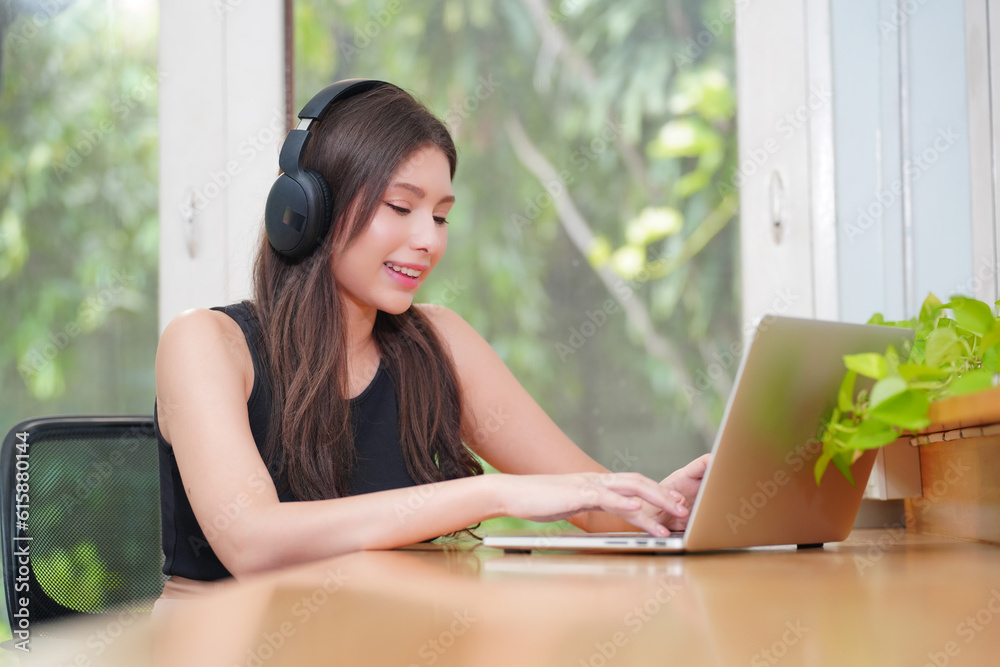 Obraz premium Young women using laptop and listening song in on-ear headphones.