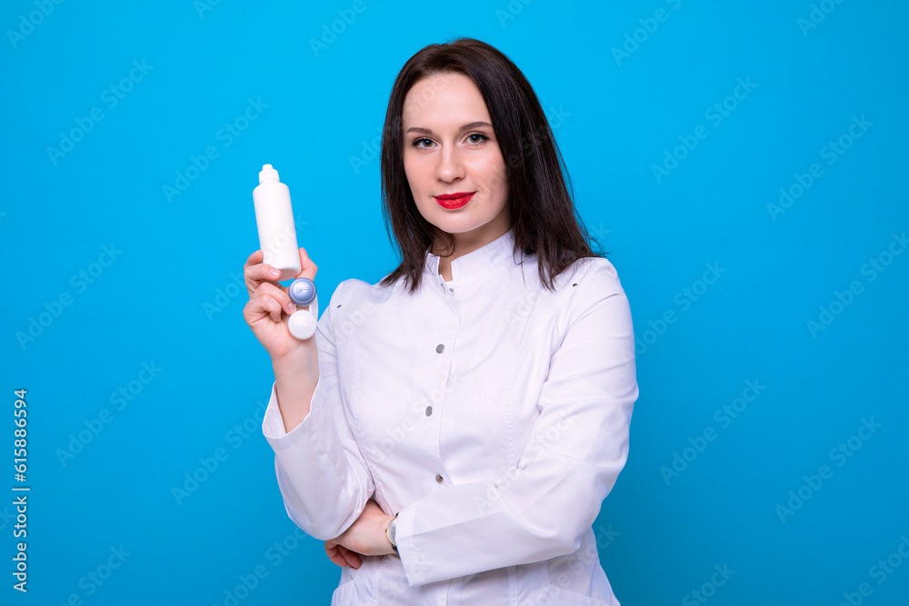 Female ophthalmologist doctor with a lens container on a blue background Female ophthalmologist doctor with a lens container on a blue background