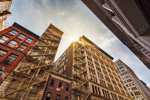 Narrow alley with Old apartment buildings and fire escapes on a sunny day in Midtown Manhattan, New York City