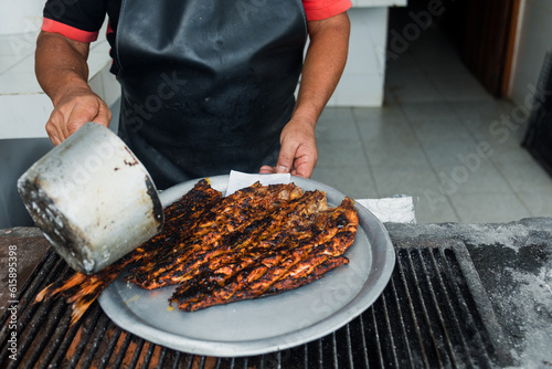 hands of mexican man cooking grilled fish traditional from Acapulco Mexico or barbecued fish called “Pescado a la Talla” seafood