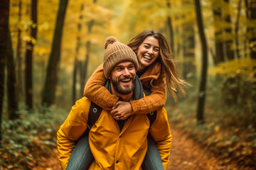 Happy couple piggybacking in a forest one autumn afternoon