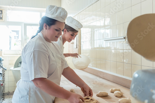 Women in bakery forming raw dough to pretzels for later baking