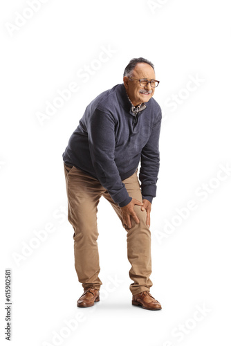 Mature man standing and holding his painful knee