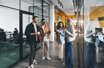 Diverse colleagues discussing ideas during break in office corridor