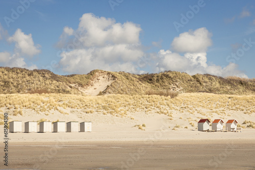 Fototapeta Naklejka Na Ścianę i Meble -  tiny white beach houses and dunes under a blue clouded sky at the beach of Westenschouwen, The Netherlands