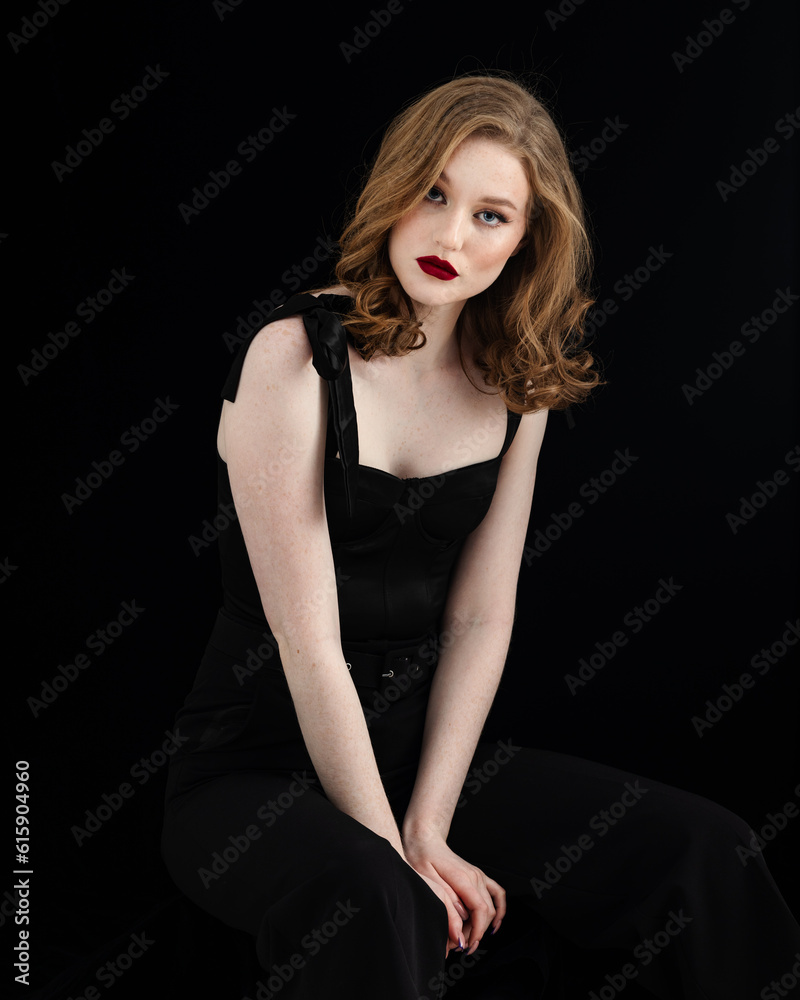 Beauty theme portrait of a beautiful young girl model with freckles on her face in a black dress and black pantyhose on a dark background in the studio Beauty theme portrait of a beautiful young girl model with freckles on her face in a black dress and black pantyhose on a dark background in the studio