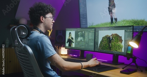 Young 3D designer draws video game character, creates animation. Teenager works remotely at home on computer and big digital screen with professional software interface for 3D modeling and design. photo