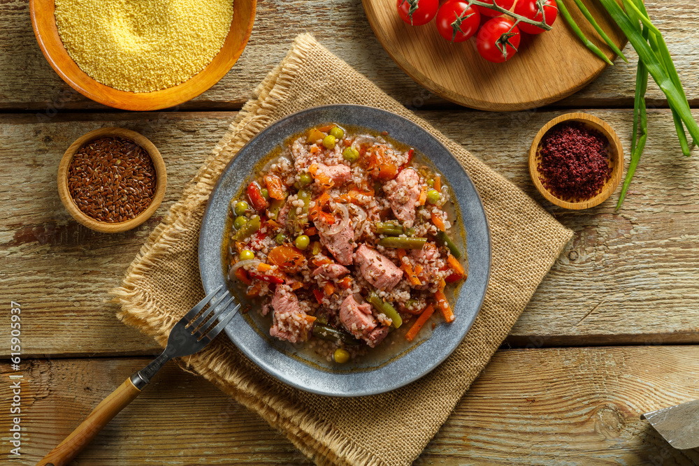 Israeli couscous with sumac and pieces of stewed chicken on a table on a linen napkin in a plate next to spices and vegetables Israeli couscous with sumac and pieces of stewed chicken on a table on a linen napkin in a plate next to spices and vegetables