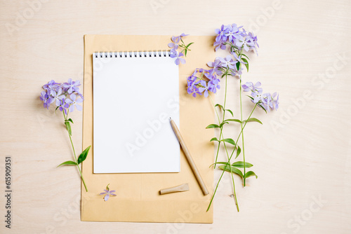 Summer mockup scene. Blank notebook  pen and blue flowers on a wooden background.
