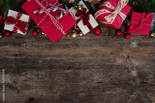 Christmas gift giving concept - christmas presents in red and white boxes with ribbons on wooden table, flat lay with copy space