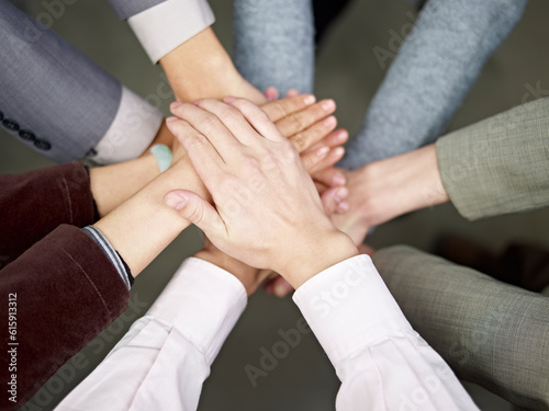 team of businesspeople showing unity by putting hands together.