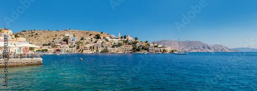 Fototapeta Naklejka Na Ścianę i Meble -  Symi also known as Syme or Simi is a Greek island one of the Dodecanese islands. Beautiful Symi Yialos town in bay and on the mountains on sunny summer day.