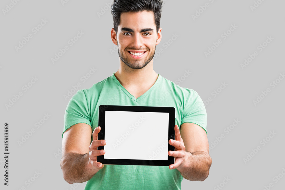 Handsome young man showing something on a tablet, isolated over gray background Handsome young man showing something on a tablet, isolated over gray background