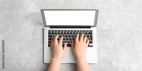 Hands of woman using laptop on light background, top view