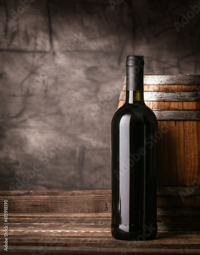 Fotografie Red wine bottle and wooden barrel in the cellar, traditional wine making and tas
