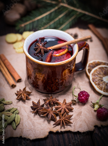 mulled wine in a brown ceramic cup on a brown sheet of paper with ingredients and spices