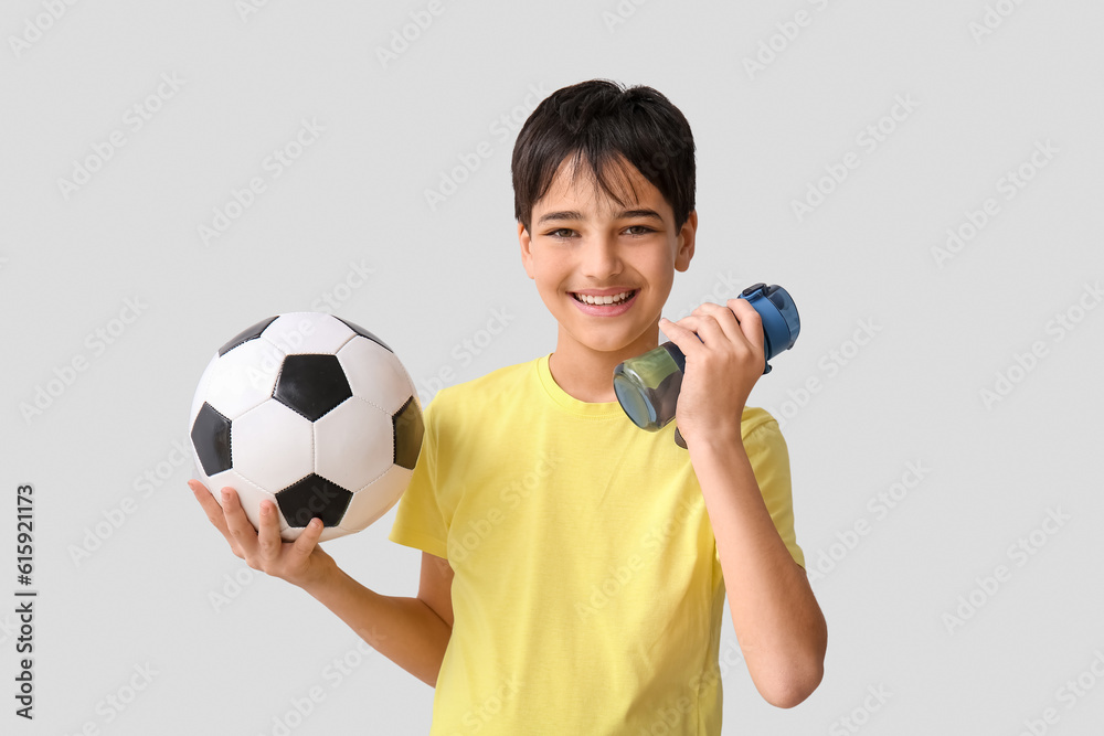 Little boy with soccer ball and bottle of water on grey background Little boy with soccer ball and bottle of water on grey background