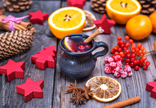 Fototapeta Naklejka Na Ścianę i Meble -  mulled wine in a brown ceramic mug on a gray wooden background, beside ingredients and Christmas decor