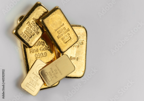 Several gold bars of different weight on a gray surface.