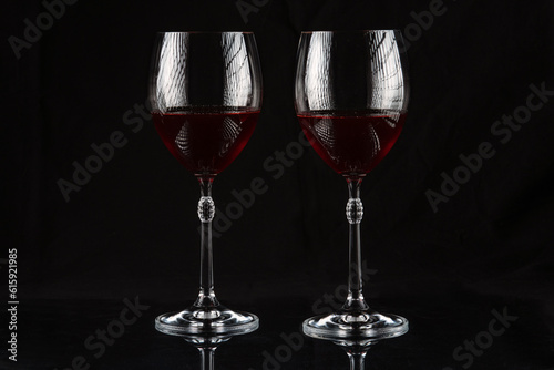 Two wine glasses with red wine on a dark background.